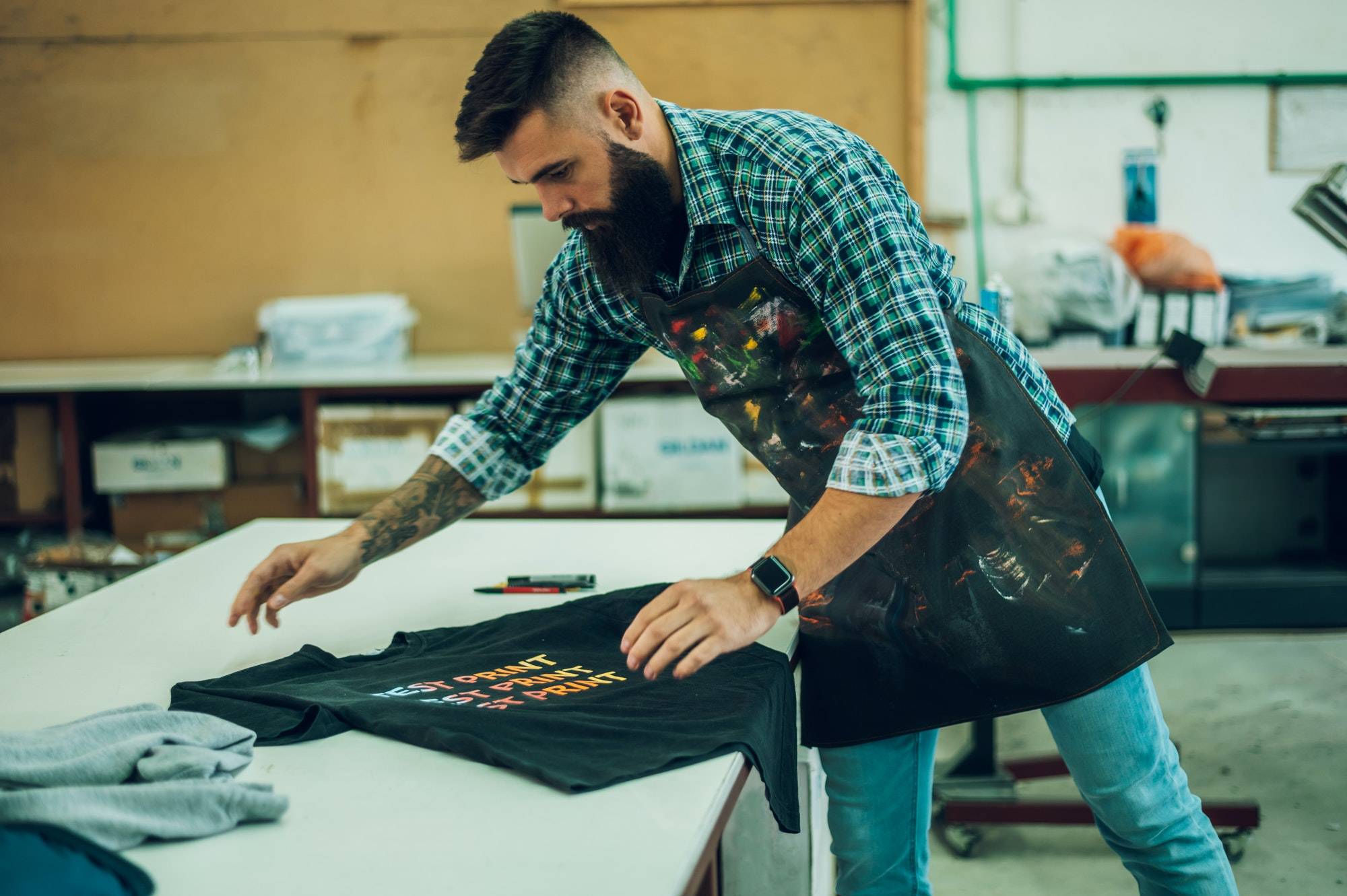 Male worker folding a fresh printed t shirt in a printing workshop